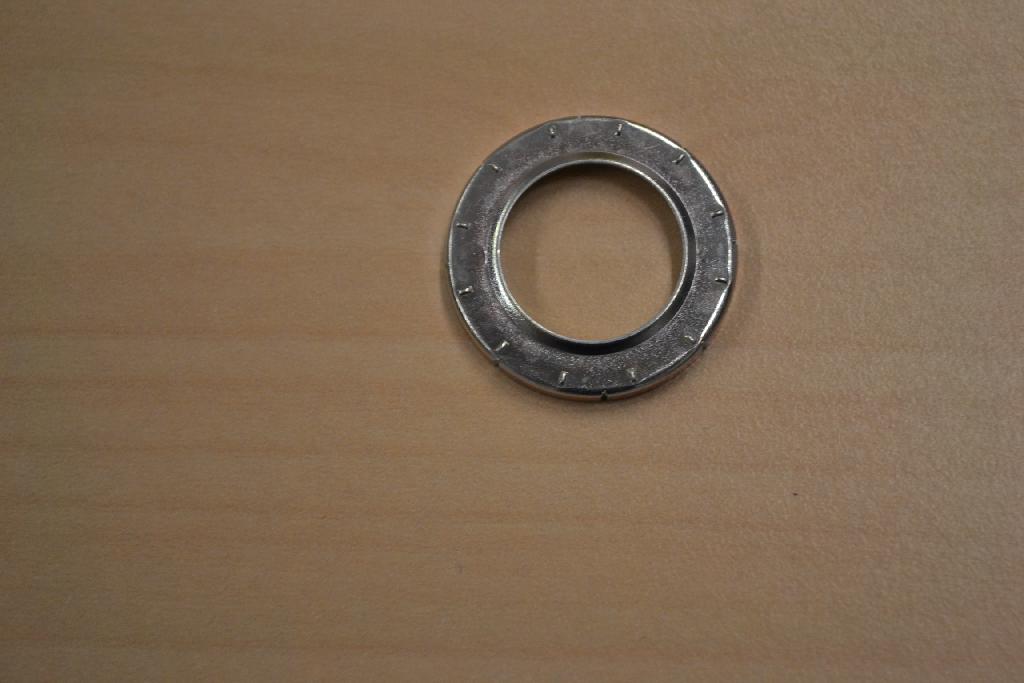 Een ring met -volgens opgave- onder meer de volgende kenmerken:
- bestemd als afsluitring in een airco;
- vervaardigd van ijzer of staal, geplateerd met zink met een dikte van 5 tot 10 µm;
- een buitenste diameter van ongeveer 2,4 cm, een inwendige 
  diameter van ongeveer 1,5 cm, een opstaande rand van ongeveer 0,2 
  cm aan de buitenzijde en een opstaande rand van ongeveer 0,05 cm 
  aan de binnenzijde;
- de opstaande rand aan de buitenzijde is voorzien van 8 verticale 
  inkepingen van ongeveer 0,2 cm;
- de bovenzijde van de ring is voorzien van 12 horizontale 
  uitsteeksels van ongeveer 0,15 cm.