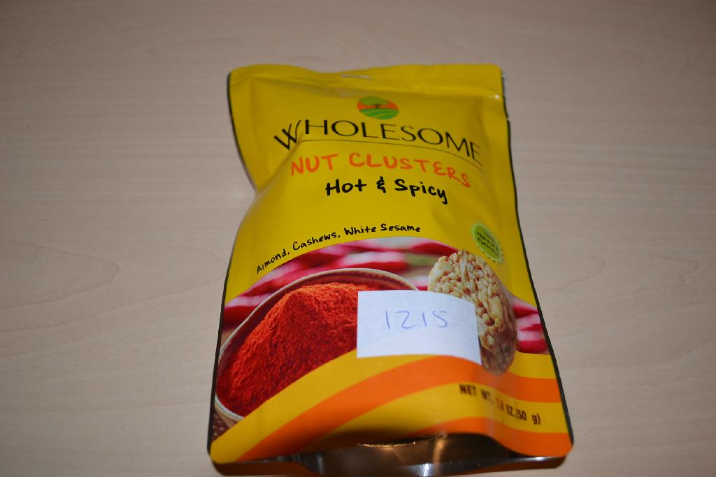 Een mengsel van noten en zaden, in de vorm van een rond schijfje, -volgens opgave- onder andere de volgende ingrediënten bevattend:
- gesneden amandel en stukjes amandel;
- cashewnoten;
- wit sesamzaad;
- suiker;
- glucosesyroop;
- rijstolie;
- hot & spicy poeder;
- natuurlijke aroma;
- zeezout;
- soja lectine;
- natuurlijke vitamine E;
- citroenzuur;
Het betreft een mengsel van andere noten en zaden met een gehalte aan tropische noten van minder dan 50 gewichtspercenten, op andere wijze bereid of verduurzaamd, in een verpakking van niet meer dan 1 kg, gebrand. Indeling onder hoofdstuk 8 kan niet plaatsvinden, omdat er bewerkingen zijn uitgevoerd die verder gaan dan toegestaan onder dit hoofdstuk.