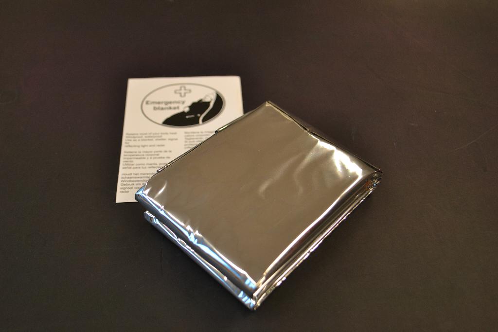 Een zilverkleurig vel folie met onder meer de volgende kenmerken:
- vervaardigd van polyethyleentereftalaat;
- in rechthoekige vorm;
- een dikte van minder dan 0,35 mm
- windbestendig;
- waterdicht;
- reflecteert licht;
- reflecteert radarsignalen;
- afmetingen van 208 x 130 cm.
Het artikel wordt gebruikt als reddingsdeken om een slachtoffer op temperatuur te houden. Het artikel is opgemaakt voor de verkoop in het klein en wordt aangeboden in een zakje van kunststof.