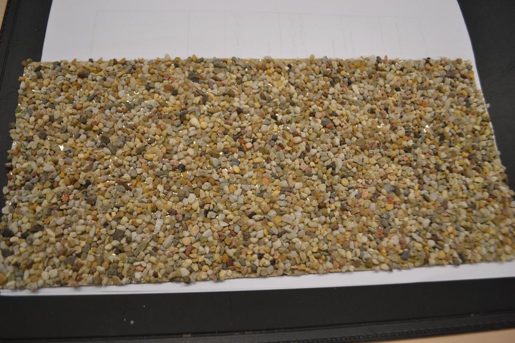 Steenfolie met onder meer de volgende kenmerken:
- een drager van textielvlies;
- een laag lijm;
- ingebed 2-4 mm maasgrind;
- een afmeting van 30 x 14 cm.
De steenfolie wordt gebruikt als decoratie. Het wezenlijke karakter wordt toegekend aan het steen.