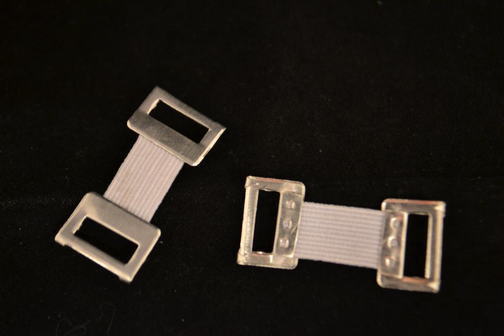 Een verbandklem bestemd voor het fixeren van een windsel of bandage. Bestaande uit 2 beugels (van 1,5 bij 1 cm) elk voorzien van 2 weerhaakjes van aluminium die zijn verbonden door elastiek. Totale lengte 3 tot 3,5 cm. De verbandklemmetjes zijn per 6 stuks verpakt in een plastic zakje. 
Het product wordt aangemerkt als een bevestigingsmiddel van aluminium.