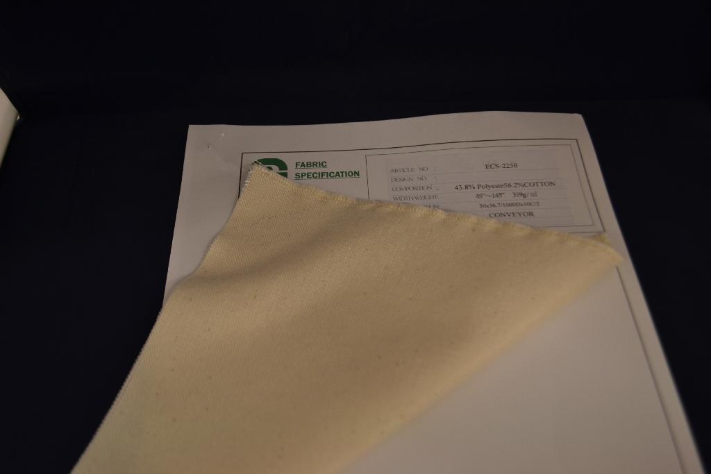 Een weefsel met -volgens opgave- onder andere de volgende kenmerken:
- vervaardigd van katoen en polyester;
- met een platbinding;
- van verschillend gekleurd garen;
- bevattende minder dan 85 gewichtspercenten katoen, enkel of
  hoofdzakelijk met synthetische of kunstmatige vezels gemengd;
- met een gewicht van 334,6 g/m²;
- met een breedte variërend van 114 tot 368 cm;
- in vellen of op rollen.
Het weefsel is bestemd voor de fabricage van transportbanden die op maat worden gemaakt.