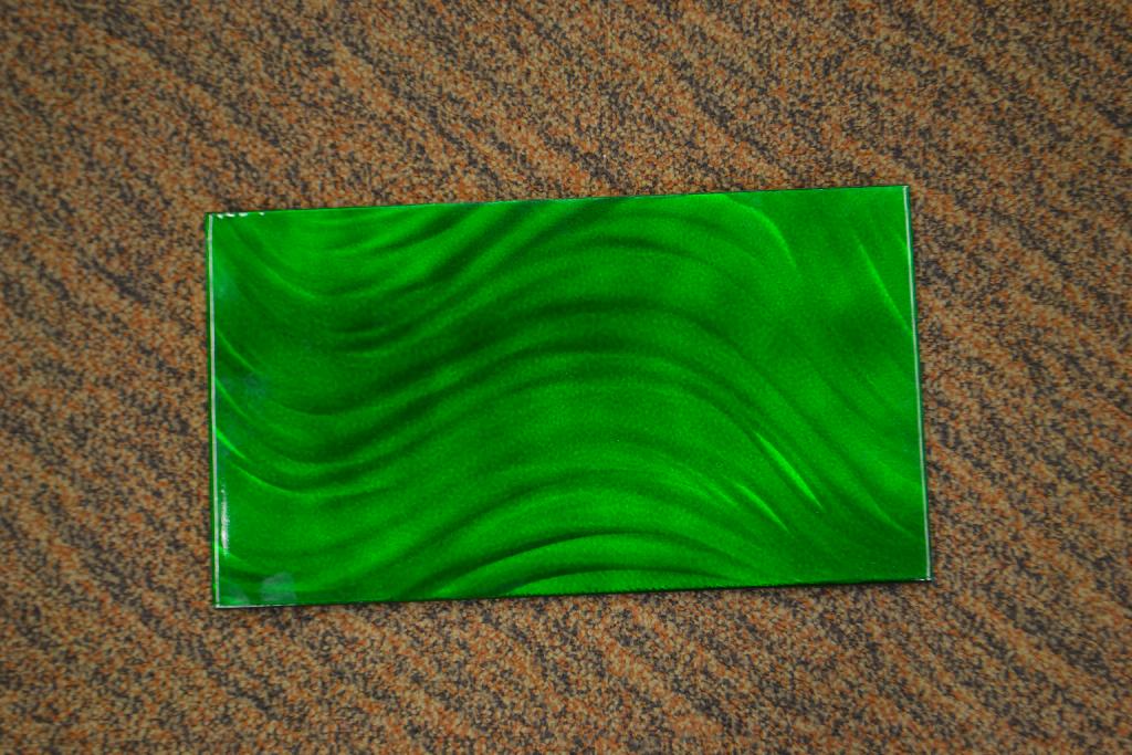 Een paneel met -volgens opgave- onder andere de volgende kenmerken:
- vervaardigd van een gesneden plaat aluminium;
- voorzien van omgebogen randen;
- een patroon dat door middel van met de hand bediende borstels, slijptollen en/of dremels is 
  aangebracht; 
- beschilderd met behulp van een airbrush;
- een UV beschermende laklaag.
Gelet op de aanbiedingsvorm is het paneel voor de indeling in de nomenclatuur te beschouwen als een voorwerp met een commercieel karakter en moet daarom worden ingedeeld naar het materiaal waaruit deze bestaat. Het paneel wordt ingedeeld als een ander werk van aluminium onder GS-post 7616 van de gecombineerde nomenclatuur.