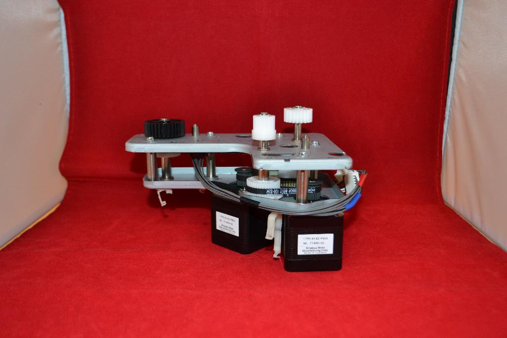 Een zogenoemde printer drive, zijnde een tandwielkast, met onder meer de volgende uiterlijke en technische kenmerken:
- 2 metalen platen, speciaal gevormd (L-vormig), voorzien van bevestigingsgaten;
- daartussen diverse tandwielen, vervaardigd van kunststof, in verschillende maten en deels met elkaar 
  verbonden door getande riemen;
- 2 –volgens opgave- mechanische motoren;
- aansluitkabels;
- bestemd voor een bepaald type printer.
Het artikel heeft de functie het papier door te voeren in samenwerking met –volgens opgave- een controller.