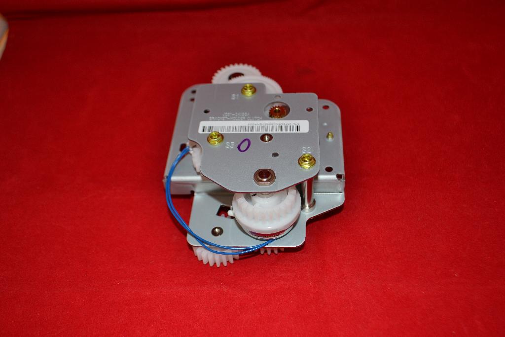 Een zogenoemde printer exit drive, zijnde een tandwielkast, met onder meer de volgende uiterlijke en technische kenmerken:
- 2 metalen platen, speciaal gevormd voorzien van bevestigingspunten;
- tandwielen, vervaardigd van kunststof, in verschillende maten en met verschillende inkepingen;
- een aansluitkabel;
- een –volgens opgave- mechanische motor;
- een printplaatje met een aansluitstekker;
- bestemd voor een bepaald type printer.
Het artikel heeft de functie het papier door te voeren in samenwerking met –volgens opgave- een controller.