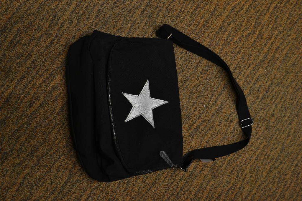 Een tas met een buitenzijde van textiel met onder meer de volgende kenmerken:
- model postbodetas;
- geschikt voor het bergen van documenten, groter dan het model A4; 
- voorzien van een verstelbare schouderband;
- gevoerd;
- in de overslag voorzien van een ruimte die afsluitbaar is met een ritssluiting;
- binnen aan de voorzijde in de voering voorzien van 2 steekvakken;
- binnen aan de achterzijde in de voering voorzien van een vak met een ritssluiting;
- voorzien van een magneetsluiting;
- op de overslag is een versiering opgestikt.