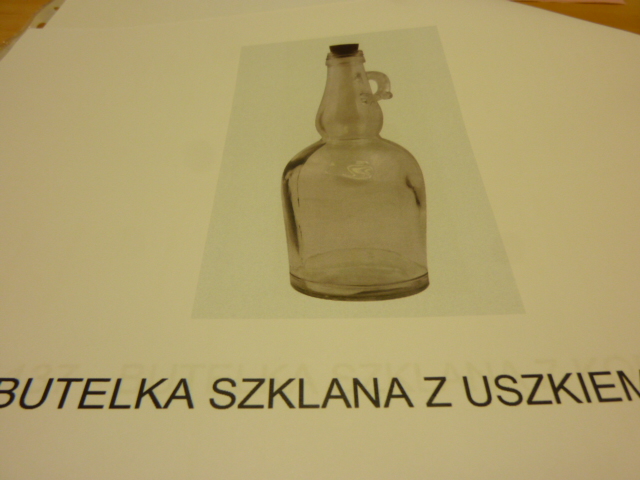 Butelka o zaokrąglonej lub kwadratowej  podstawie, ze szklanym uszkiem lub bez, z zamknięciem z korka. Naczynie szklane wykonane z bezbarwnego szkła sodowo-wapniowego, z wytłoczonym wzorem. Posiada specjalnie wyprofilowaną krawędź otworu, na którą nakładany jest specjalnie dopasowany wyprofilowany korek. Korek dociskany jest do butelki. Zgodnie z deklaracją Wnioskodawcy wyrób przeznaczony jest do pakowania soków, wody. Pojemność: 500 ml, 700 ml.