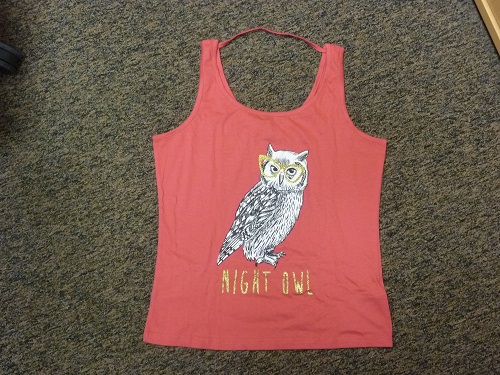 Koszulka na ramiączka wykonana z dzianiny bawełnianej w kolorze różowym, na przodzie nadrukowany jest obrazek sowy oraz napis „NIGHT OWL”. Koszulka posiada półkoliste wycięcie pod szyją, w tylnej części jest wszyta tasiemka łącząca ramiączka, dół zakończony przez podwinięcie. Produkt występuje w zestawie jako piżama z krótkimi i długimi spodenkami  (spodenki i spodnie klasyfikowane odrębnie). Prezentowane w opakowaniu z folii z tworzywa sztucznego. Prezentowane w opakowaniu z folii z tworzywa sztucznego.