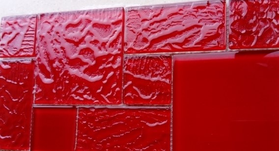 Mozaika wykonana z płytek szklanych. Tafle szkła pocięte na elementy o wymiarach 46,5 x 46,5 mm - 8 szt.,  95 x 95 mm - 4 szt., 95 x 46,5 mm - 6 szt., umieszczone są na podłożu - siatce z tworzywa sztucznego - i połączone za pomocą kleju, tworząc mozaikę o wymiarach 296 x 296 mm, o grubości 6 mm. Elementy szklane mogą być malowane od spodu lub posiadać okleinę dekoracyjną. Artykuł przeznaczony do przyklejania na ścianę wewnątrz pomieszczeń. Prezentowany w zbiorczym opakowaniu kartonowym po 5 -11 szt.