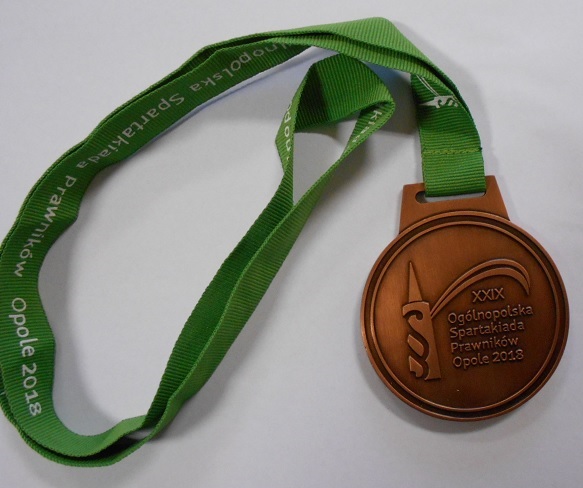 Medal sportowy w kształcie pełnego koła o średnicy ok. 70 mm, wykonany ze stopu cynku, aluminium i miedzi, pokryty farbą emaliową koloru brązowego, nie zawierający kruszców szlachetnych, opatrzony oczkiem do nawleczenia wstążki i posiadający taką wstążkę, jako integralna część. Medal posiada wzornictwo sportowe. Wstążka w kolorze zielonym wykonana z poliestru z nadrukiem w kolorze białym (logo + napis). Medal służy do dekorowania zwycięzców (I, II, II miejsce) za osiągnięcia sportowe i stanowi materialne trofeum, jako dowód zdobycia konkretnej lokaty lub miejsca w zawodach sportowych.