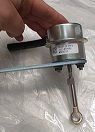 Siłownik pneumatyczny składający się z cylindrycznego zasobnika wykonanego z cienkościennej, formowanej blachy, zawierającego wewnątrz gumowe membrany oraz sprężynę. Ze ściany bocznej wyprowadzona jest gięta rurka, z dolnej wyprowadzono pręt gwintowany. Urządzenie odpowiada za sterowanie zespołem zaworu wahadłowego turbosprężarki. Sterowanie jest pneumatyczne, przy pomocy powietrza pochodzącego z obudowy kompresora turbosprężarki. Siłownik montowany jest na obudowie turbiny i połączony z mechanizmem zespołu zaworu wahadłowego turbiny poprzez drążek wykonawczy. Zadaniem jest poprawa sprawności silnika, redukcja emisji spalin poprzez wykorzystanie energii gazów wydechowych oraz sterowanie prędkością obrotową turbiny. Wymiary max ok 138 mm x 135,7 mm x 104,9 mm.