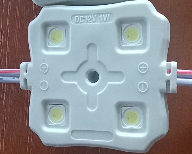 Elementy oświetleniowe w postaci modułów, zawierające cztery diody LED 5050 z układem wyrównującym napięcie, umieszczone na płytce drukowanej PCB. Produkty posiadają szczelną, wodoodporną obudowę z tworzywa sztucznego, podklejoną od spodu taśmą 3M. Na obu końcach wyposażone zostały w przewody elektryczne, które umożliwiają łączenie modułów w łańcuchy i/lub podłączenie do zasilacza (niebędącego przedmiotem niniejszej decyzji). Produkt stosowany jest do podświetlenia mebli, sufitów, schodów, wnętrza samochodów. Zasilanie 12 VDC, pobór mocy: 1,065 W. Wymiary modułu (w mm): 54,8 x 33,2 x 5,9. Produkt pakowany jest w łańcuchach po 20 szt, następnie w torebki foliowe po 100 szt i kartony - 600 szt.