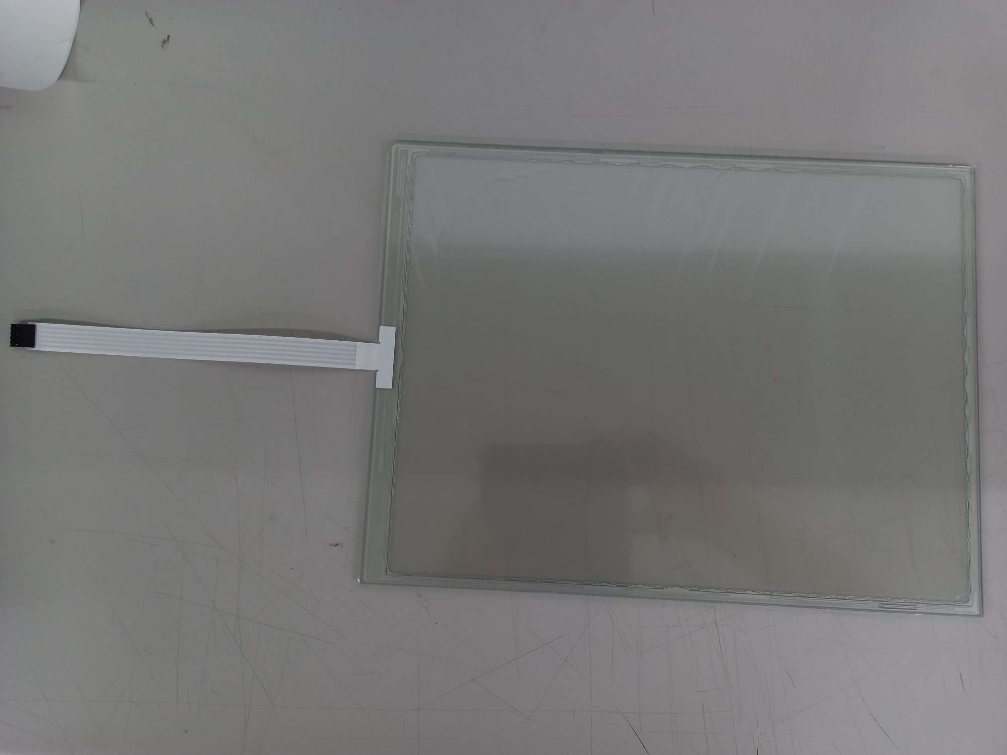 Analogowy, rezystancyjny panel dotykowy (touch panel). Ekran dotykowy wykonany w technologii oporowej i przeznaczony do stosowania ogólnego. Nie jest produkowany z przeznaczeniem do montażu w konkretnych urządzeniach elektronicznych. Składa się z dwóch warstw: wierzchniej ochronnej, z tworzywa sztucznego oraz wewnętrznej, wyposażonej w elektrody wytwarzające słabe pole elektryczne. Panel wyposażony jest w siatkę przewodów elektrycznych i łączniki. Dotknięcie ekranu powoduje odprowadzenie części ładunku i zmianę pola elektrycznego, co pozwala określić pozycję palca (dotyku). Wewnętrzna strona produktu połączona jest z elastyczną płytką drukowaną, umożliwiającą wymianę informacji pomiędzy panelem dotykowym a płytą główną. Wymiary: 332,90 x 248,90 mm.
Decyzja wydana powtórnie w miejsce decyzji numer PL BTI WIT-2020-001120.