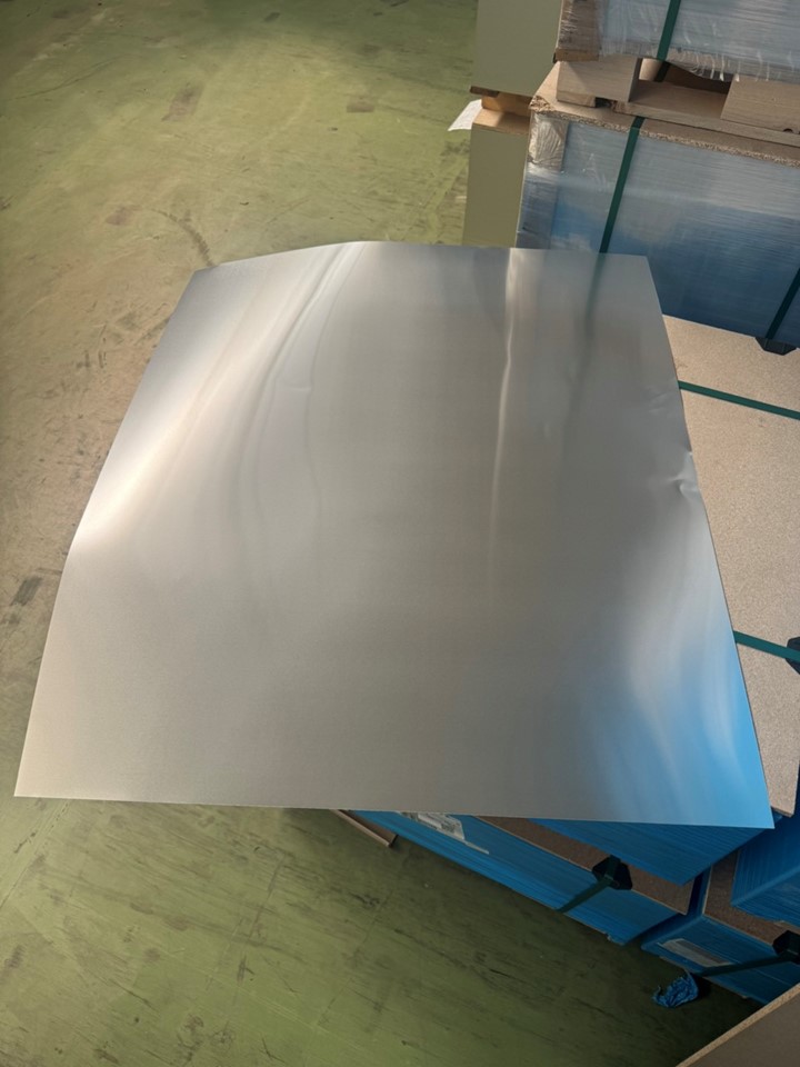 Arkusze blachy aluminiowej o przybliżonych wymiarach 1051,85x888,91x0,225 mm oraz 999x800,1x0,215 mm; o pełnym prostokątnym przekroju poprzecznym, który jest jednakowy na całej długości wyrobu. Wykonane ze stopu aluminium EN AW-8011A, o twardości H14. Wyrób jest walcowany na zimno, nielakierowany, poddany obróbce powierzchniowej zamykającej „pory” metalu polimerem tytanu, chromu lub cyrkonu w celu poprawy adhezji w późniejszych procesach obróbki (m.in. lakierowania). Obróbka powierzchniowa blachy obejmuje mycie alkaliczne, trawienie, czyszczenie wodą, chromianowanie oraz tzw. obróbkę DOS – pokrywanie blachy substancjami smarnymi, które zmniejszają siły przylegania blachy do blachy w stosie, zwiększając poślizg. Blachy nie posiadają wewnętrznych warstw innego materiału. Wyrób jest wykorzystywany do produkcji zakrywek aluminiowych – zamknięć do butelek.
