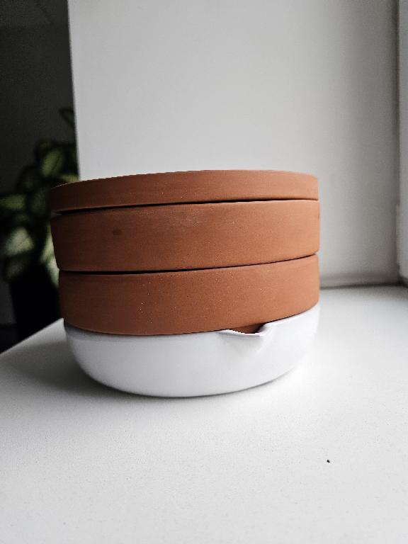 Wyrób ceramiczny w postaci czterech okrągłych tacek wykonanych ręcznie z terakoty. Ustawiane jedna na drugiej tworzą kiełkownice. Trzy górne tace mają otwory w dnie, przez które może odpływać nadmiar wody. Dolna taca jest dodatkowo szkliwiona i służy jako zbiornik na tą wodę. Kiełkownica jest przeznaczona do domowej uprawy kiełków. Produkt został uformowany ręcznie z gliny, następnie wypalony w temperaturze ok. 1150 °C.  Otwory w dnie wyznaczają wartość użytkową produktu jako tacek do uprawy roślin, prze co nie mają charakteru ozdobnego pozycji 6913. Wymiary: średnica 14 cm, wysokość 13,5 cm. Masa: 1360 g. Każda tacka pakowana osobno w foliową torebkę i pudełko, a następnie komplet 4 tac w 4 pudełkach umieszczony w jednym kartonie zbiorczym zadrukowanym informacjami o produkcie.