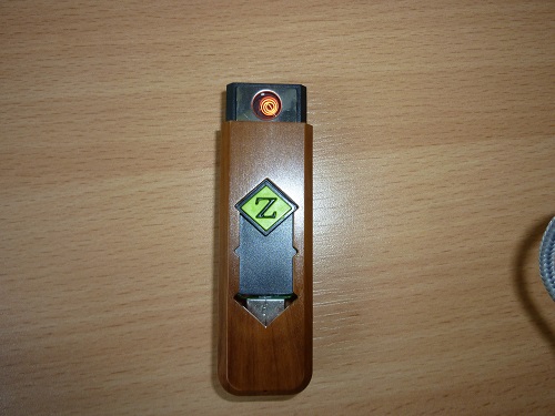 Zapalniczka elektroniczna, wykonana z tworzywa sztucznego, ładowana za pomocą złącza USB. Wymiary: ok. 8 x 3 x 2 cm.