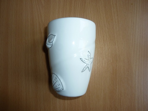 Kubek kosmetyczny o wymiarach przy górnej krawędzi ok. 6,8 cm x 5,3 cm, wymiary podstawy ok. 6,0 cm x 4,5 cm i wysokości ok. 10 cm, wykonany z ceramiki w kolorze białym, szkliwiony. Produkt o cechach charakterystycznych dla porcelany. Kubek przeznaczony do przechowywania akcesoriów łazienkowych, np. wacików, patyczków kosmetycznych.