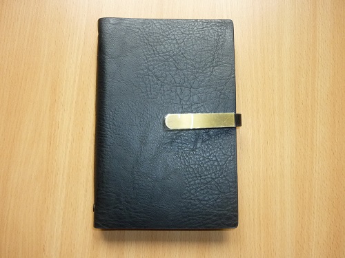 Organizer formatu A6. Produkt składa się z okładki wykonanej z tworzywa sztucznego (poliuretan) imitującego skórę, zamykanej przy pomocy klapki z zatrzaskiem oraz wkładu papierowego. Po wewnętrznej stronie okładki przymocowana jest kieszonka z trzema przegródkami na wizytówki i uchwyt na pióro, wewnątrz zamocowany jest metalowy ring. Wkład papierowy składa się z 80 kartek, które zawierają skrócony kalendarz, adresownik oraz notatnik.