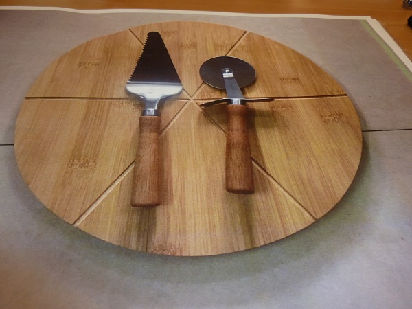 Zestaw do serwowania pizzy. W skład zestawu wchodzą: bambusowa okrągła deska do pizzy o wymiarach 33 x 1,5 cm, radełko ze stali nierdzewnej z bambusową rączką o wymiarach 19 x 6,5 cm oraz łopatka do pizzy ze stali nierdzewnej o wymiarach   24,5 x 6 cm.