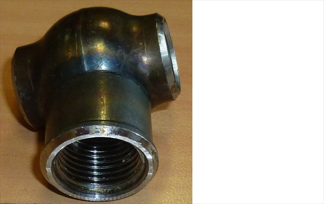 Łącznik trójprzelotowy w kształcie litery "T", wykonany ze stali niestopowej bez zastosowania procesu odlewania, o gładkich metalicznych powierzchniach, przeznaczony do zamontowania w nieelektrycznych panelach grzewczych. Dwa jednakowe króćce położone współosiowo są zewnętrznie sfazowane. Trzeci króciec położony prostopadle do dwóch pozostałych jest nagwintowany wewnętrznie półcalowym gwintem rurowym walcowym G1/2. Króćce sfazowane są łączone z panelami grzejnika poprzez spawanie lub zgrzewanie doczołowe, natomiast w króćcu nagwintowanym, w zależności od potrzeb, są montowane złącza doprowadzające lub odprowadzające czynnik grzewczy, odpowietrznik lub korek zaślepiający. Orientacyjne wymiary gabarytowe wyrobu wynoszą: wysokość około 5 cm, szerokość około 4 cm, a grubość około 3,5 cm.