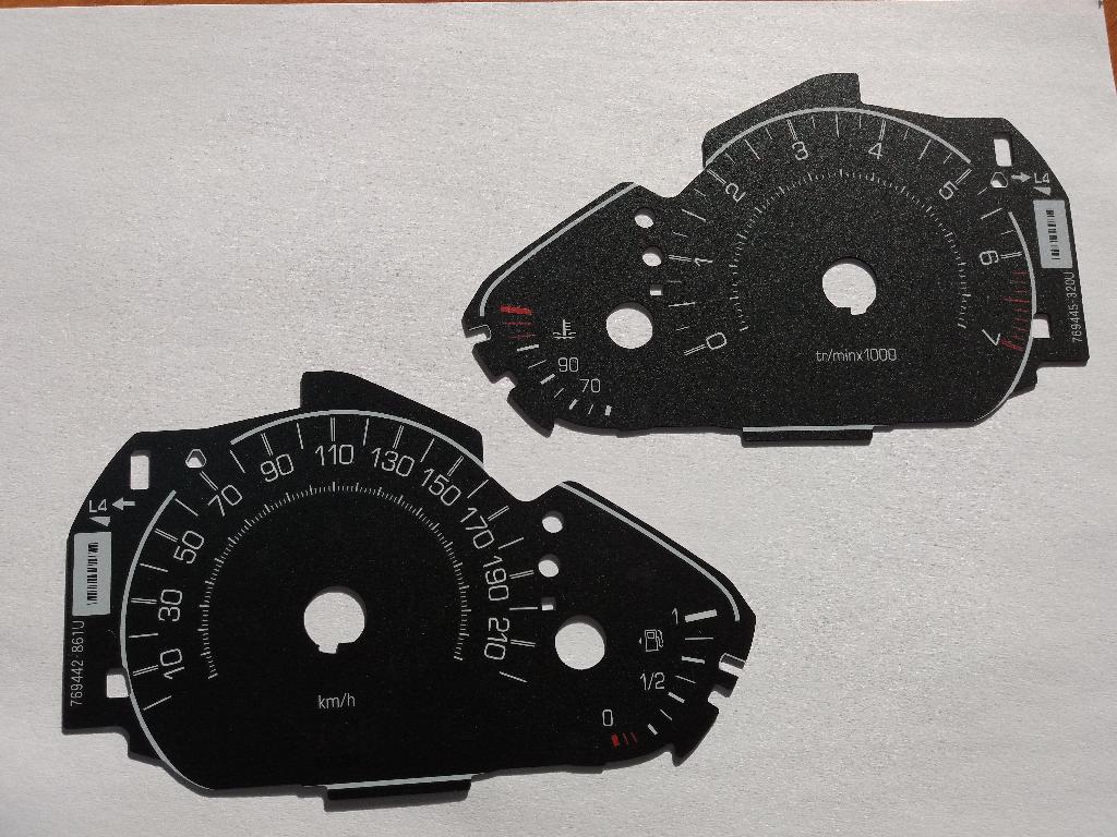 Conform descrierii solicitantului şi a mostrei ataşate, produsul reprezintă o parte de indicator de bord pentru autovehicule (cadran pentru indicator de bord auto). Cadranul este o componentă a indicatorului de bord auto (indicator de viteză, turaţie, sau alte indicatoare similare), pe care sunt aplicate mai multe straturi de vopsea şi prezintă înscrisuri, semne sau cifre care oferă diferite informaţii utile, cum ar fi viteza autovehiculului sau numărul de rotaţii pe minut. Se prezintă în diferite forme decupate specific fiecărui indicator utilizat în montajul tablourilor de bord auto.Este confecţionat din policarbonat.