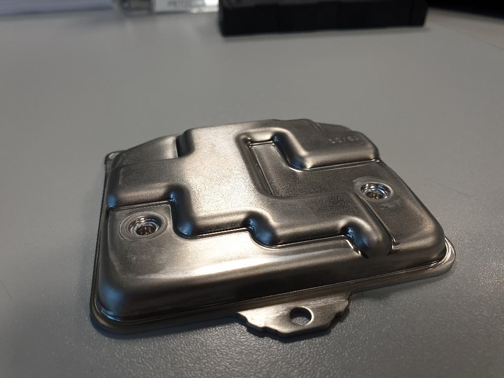 Conform descrierii solicitantului și a fotografiilor publicate în baza de date, produsul reprezinta o parte a unei unităţi de control electronice pentru autoturisme (LCM – light control module). 
Este confecţionată din aluminiu şi are rolul de susţinere şi protecţie a unui ansamblu electronic care va fi montat ulterior (nu face obiectul prezentei decizii). Partea de aluminiu este prinsă de o carcasă de plastic ( nu face obiectul prezentei decizii ITO) cu un sistem de cleme.
.
Dimensiune: 90,5x88x11,7 mm, grosime 1,5 mm