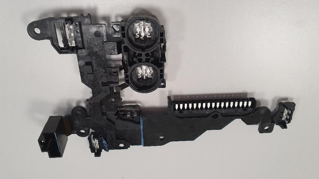 Produsul reprezintă un ansamblu format din conductori de cupru inglobati prin turnare intr-un invelis de material plastic şi denumit cadru pentru senzorul de presiune. Ansamblul este o componenta pasiva a modulului electronic de control al cutiei automate de viteza care realizeaza doar conexiunea electrica dintre diferitele subansamble ale modulului, fiind o parte a acestuia.
Componenta este proiectata sa asigure transmiterea semnalelor electrice de la senzorii de presiune si pozitie montati pe modulul electronic de control al cutiei automate de viteze catre unitatea centrala de procesare a respectivului modul.
Conductorii sunt proiectati pentru transmiterea unui semnal electric cu tensiunea maxima de 30 V.C.C si 1500 de mA.
Produsul vine pe palet de lemn ambalat in cutii de carton avand in interiorul unei cutii cate 64 de buc.
