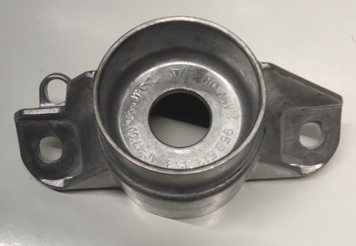 Produsul reprezintă o piesă metalică de formă neregulată, cu o secţiune longitudinală goală la interior, din aliaj de aluminiu DIN 1688-4 GTA13/5 / ISO 8015.
Reprezintă o parte a unei piese de tip “ansamblu” cu rol antivibraţii (AVS – “anti vibration system”) ȋn cadrul sistemului de suspensie al unui autovehicul și care asigură partea care preia vibraţiile/şocurile, ȋn general între elemente de caroserie şi amortizorul spate.
Caracteristici: ȋnălţimea de 71 mm, suprafaţa ȋn vedere frontală are lungimea 153 mm şi laţimea 73.5 mm, diametru interior de Ø 26 mm. La capete piesa metalică are următoarele caracteristici: urechi de prindere prevazute cu locaş prelucrat prin aşchire.
Procesul tehnologic de obţinere a piesei este cel de turnare a aluminiului ȋn lingotiere, debavurare şi prelucrare prin aşchiere.