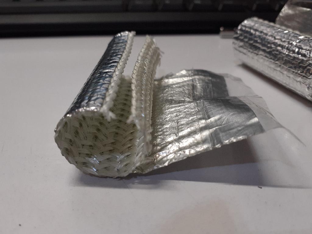 Conform descrierii solicitantului si fotografiei publicate in baza de date, produsul cu denumirea de tub reprezinta un articol finit sub forma unui manson tubular despicat, din tesatura de fibra de sticla acoperita cu poliester si imbracata la exterior cu o folie din aluminiu.
Materialul compozit cu rol izolator are grosimea de 0,94mm si este modelat in forma cilindrica / tubulara cu laterala deschisa (si marginile tesaturii finisate), cu diametru de 15,8mm si lungime 120mm. 
Articolul este destinat montarii in jurul unui tub metalic din ansamblul motor al autovehiculelor, pentru a-i asigura acestuia protectia termica fata de componentele generatoare de caldura din imediata lui apropiere. 
Mod de ambalare: 1000 buc./ sac de plastic, in cutii de carton. 
Produsul nu poate fi recunoscut ca fiind destinat exclusiv domeniului declarat. Caracterul esential este dat de tesatura de fibra de sticla cu rol izolator.