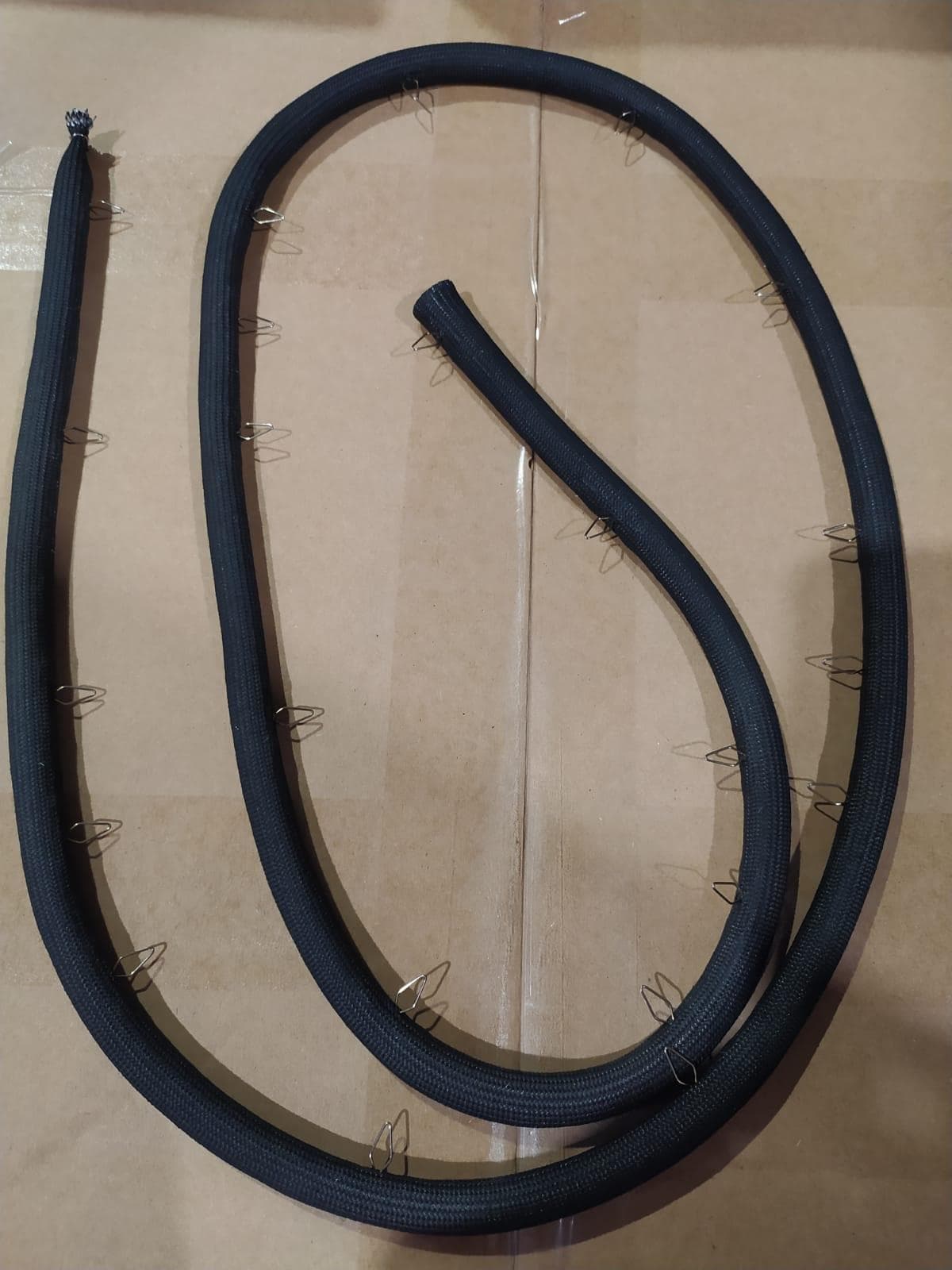 Conform descrierii puse la dispozitie de solicitant si imaginilor publicate in baza de date, produsul denumit ”Garnitura pentru usa cuptor” reprezinta un articol compozit cu aspect tubular si cleme metalice, utilizat pentru masinile de gatit casnice ce au cuptoare electrice.
Este alcatuit dintr-un manson exterior din tesatura din fibra de sticla, cu intaritura interioara tubulara din impletitura de otel inoxidabil. Intaritura tesuta din fir de otel are rolul de a pastra forma circulara a garniturii.
Pe produs sunt montate carlige de fixare din otel inoxidabil ce servesc la fixarea acestei garnituri pe fata cuptorului, prin agatarea /inserarea in gaurile existente pe aceasta. 
Produsul montat astfel intre fata si usa cuptorului asigura etanseitatea pentru cuptoarele pirolitice ce dezvolta temperaturi inalte de pana la 475°C.
Se prezinta ambalat individual.