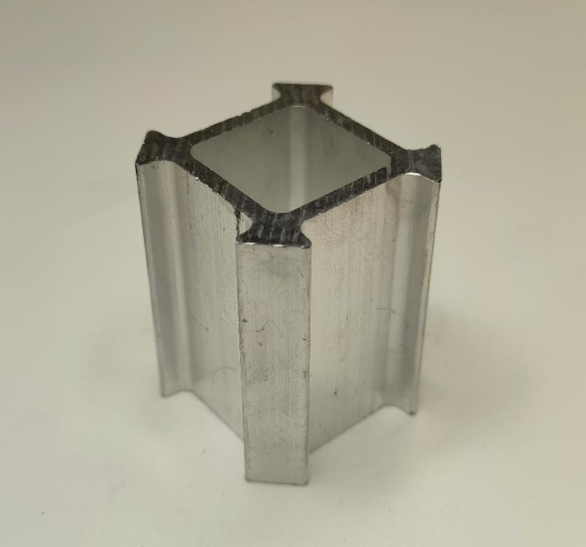 Produsul reprezintă o piesă metalică de formă paralelipipedică prevazută cu nervuri laterale, cu o sectiune paralelipipedică goala la interior, din aliaj de aluminiu EN AW-6061 T6 DIN EN 755-2.
Reprezintă o parte a unei piese de tip “bucşă” cu rol antivibraţii (AVS – “anti vibration system”) care preia vibraţiile/şocurile, ȋntre elemente de caroserie şi compartimentul motor.
Caracteristici: ȋnălţimea de 55 mm, suprafaţa ȋn vedere frontală are lungimea 51.4 mm şi lăţimea 51.4 mm, dimensiunea frontală gol interior are lungimea de 26 mm şi lăţimea 26 mm.
Procesul tehnologic de obţinere a piesei este cel de extrudare a profilului de aluminiu, tăiere (debitare la lungime).
Ulterior punerii in libera circulatie, asupra piesei se intervine cu tratamente chimice (adezivare) care asigură curăţarea de impurităţi ȋn vederea asigurării aderenţei necesare aplicării unui strat de cauciuc.
