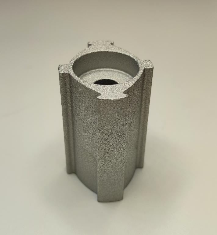Conform descrierii solicitantului și a fotografiei publicate în baza de date, produsul reprezintă o piesă metalică de formă cilindrică prevazută cu nervuri, cu o sectiune cilindrică goala la interior, din aliaj de aluminiu EN AW-6082 T6 prelucrat cu urmatoarele caracteristici: ȋnălţimea de 74.3 mm, suprafaţa ȋn vedere frontală are lungimea 58 mm şi laţimea 49.2 mm, diametru interior cu geometrie specifică de poziţionare (ȋn formă de lacrimă) de 14.1 mm. La unul din capete piesa metalică are un locaş frezat cu următoarele caracteristici: diametrul 34 mm si adâncime de 12 mm. Procesul tehnologic de obţinere a piesei dinaliaj de aluminiu este cel de extrudare profil de aluminiu, tăiere
(debitare la lungime) şi prelucrare prin aşchiere a locaşului. 
Piesa importată reprezintă o componentă a piesei antivibraţii tip “bucşă” utilizată de constructorii auto ȋn sistemele de amortizare a vibraţiilor/şocurilor, ȋn speţă această componentă auto tip “bucşă” asigură partea “elastică” care preia vibraţiile/şocurile ȋntre două componente auto rigide, ȋn general ȋntre motor şi elemente de caroserie. 
După punerea ȋn libera  circulaţie, aceste piese sunt supuse ȋn România următorului proces tehnologic: adezivarea şi vulcanizarea piesei metalice. După vulcanizare rezultă un produs finit . Anterior importului, piesa suportă prelucrări tehnologice şi constructive definitive, respectiv este prelucrată la caracteristicile tehnice şi constructive pentru montarea ȋn produsul finit (lungime, grosime, dimensiuni exterioare, diametru interior, duritate, rugozitate etc.)