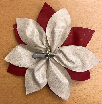 Konstgjord växt i form av en tvåfärgad blomma med en diameter av c:a 19 cm.
Blomman är avsedd att användas för dekorationsändamål.
Blomman är tillverkad av vävt textilmaterial belagt med glitter och har blomknoppar av oädel metall samt ett clips på undersidan för fastsättning.
Blommans delar är sammanfogade genom klistring och bindning med metalltråd.