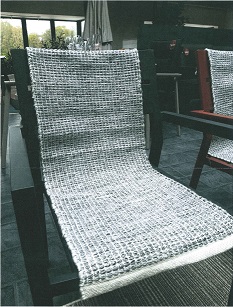 Textilvara i form av en rektangulär, tvåfärgad stolsvepa av syntetiskt textilmaterial, vävd med tvåskaftsbindning. Varan har måtten 35 x 100 cm (B x L) och tjockleken är ca 6-7 mm.
Textilvaran är enligt uppgift tillverkad av garn bestående av 100 % polyester (återvunna PET-flaskor). Varan har en bottenväv av vitt garn och ett extra inslag på ovansidan bestående av tvinnade vita och svarta garntrådar. Textilvaran är konfektionerad utan lugg och försedd med fåll och stadkant.
Stolsvepan är en vara som har karaktär av golvbeläggning av textilmaterial, men som är avsedd att användas för andra ändamål, jämför anmärkning 1 och texten i FAHS till kapitel 57.