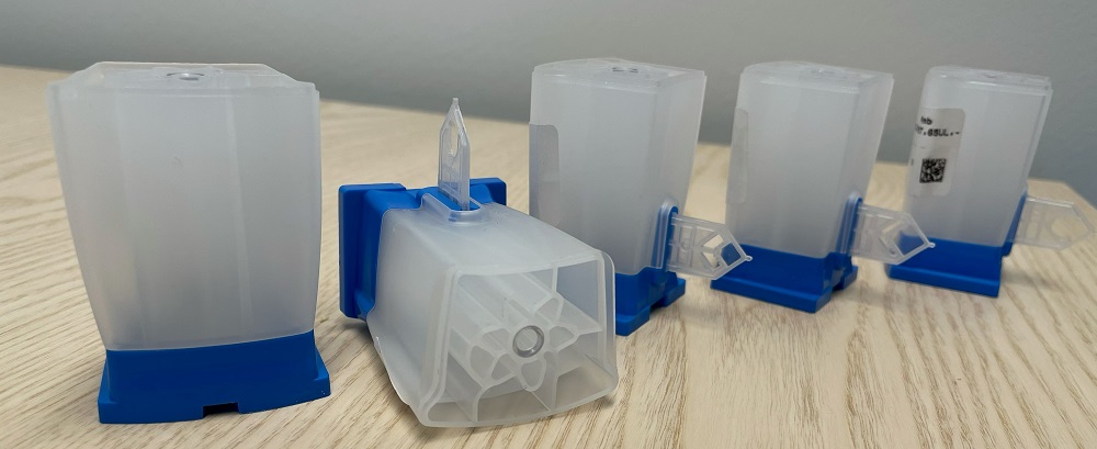 Testkassett (del till instrument)
Engångskassett för laboratorietestning, in vitro, för att påvisa förekomst av virus etc. Efter att varan är kompletterad, efter importen, med reagenser etc. och lock i fabrik så skickas den till sjukvårdens laboratorier där den laddas med prov och placeras i ett analysinstrument enligt 9027. Hela laborationen och analysen sker i behållaren (blandning, filtrering, extrahering, ultraljudsbehandling etc.) med hjälp av ventiler, filter och pistongen.
Varan består av en fot, en behållare med flera kammare, filter, ventil, pistong, en fena för behandling och analys av det extraherade provet.
Testkassetten bedöms vara oundgänglig för analysinstrumentets grundläggande funktion och inkomplett då den saknar lock.