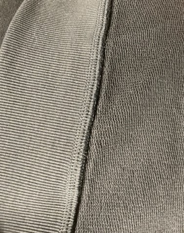 Långärmat ofodrat plagg för överdelen av kroppen i form av en enfärgad tröja (sweatshirt). Plagget är konfektionerat genom sömnad, har rund halsringning (saknar öppning och tillslutning), når ner till strax under midjan och är enligt uppgift avsett för kvinnor. Nederkanten av tröjan, halsringningen och ärmsluten är försedda med avsmalnande hopdragning i form av påsydda ribbstickade muddar.
Plagget är inte igenkännlig som en tröja för varken män eller kvinnor och anses därför vara unisex.
Tröjan är tillverkad av slätstickad dukvara av trikå som enligt isydd etikett består av 100 % bomull.
Plagget förekommer enligt uppgift i storlekarna S-XL.