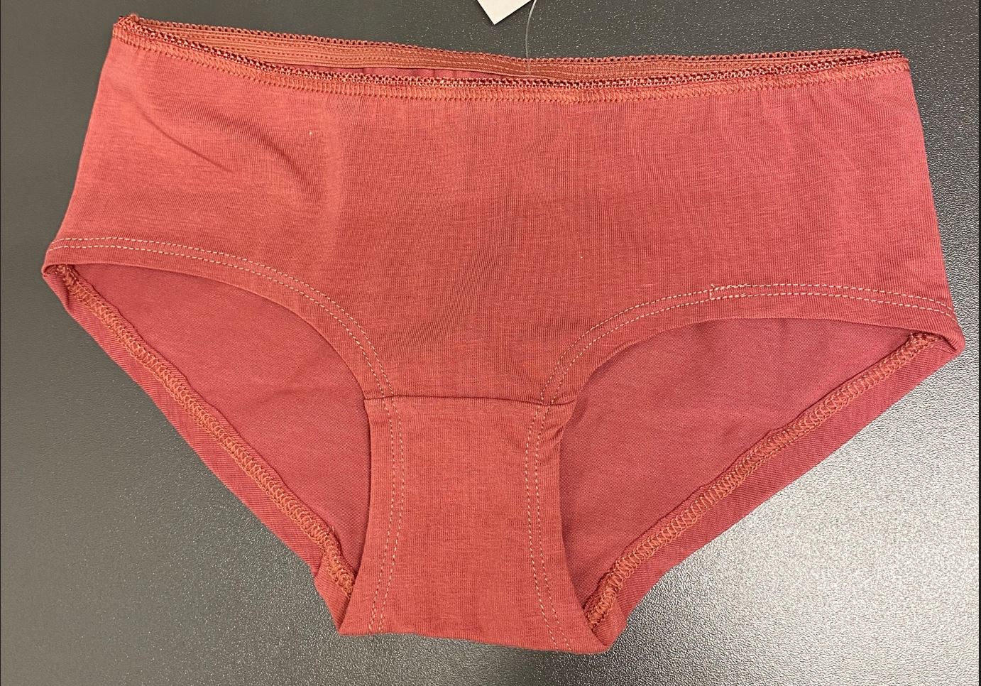 Enfärgat trikåplagg i form av en trosa för flickor. Trosan har ett påsytt elastiskt band i midjan, fodrad gren och korta ben som avslutas med fåll.
Trosan är tillverkad av dukvara av trikå som består av 95% bomull och 5 % elastan.
Varan är konfektionerad genom sömnad och förekommer enligt uppgift i storlekarna 120/130 och 140/150. Plaggets skärning utvisar klart att det är avsett för flickor.
