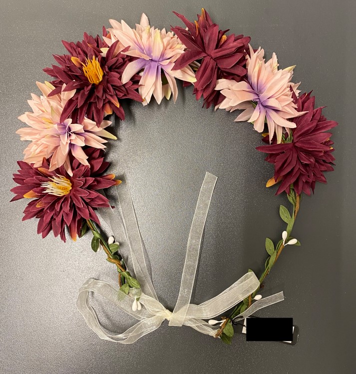 Krans försedd med konstgjorda blommor och blad.
Kransen används till att smycka håret och har ingen sammanhållande funktion för håret.
Kransens stomme består av två metalltrådar som är omlindade med enfärgat brunt respektive grönt papper och har en diameter av ca 17 cm. Kransen har bladverk av vävt textilmaterial som lindats runt stommen, vita knoppar av gips fastlindade i stommen, sju stycken konstgjorda blommor med kronblad bestående av vävt textilmaterial och gröna foderblad av plast. Blommorna är limmade på stommen. Kransens storlek kan regleras med hjälp av fastknutna textilband.
De konstgjorda blommorna av textilmaterial ger kransen dess karaktär.