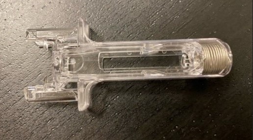 Del till manuell injektor i form av en plastkropp.
Varan är enligt uppgift avsedd att tillsammans med fylld spruta med läkemedel bilda en produkt för administrering av läkemedel. (Fylld spruta ej del av detta beslut.)
Varan utgörs av en ihålig plastvara med en invändig sammanpressad spiralfjäder av rostfritt stål.
I syfte att undvika stickskador är varan utformad för att dra tillbaka nålen efter användning.

Varans mått: Längd ca 7 cm, bredd ca 3 cm, höjd ca 1 cm.