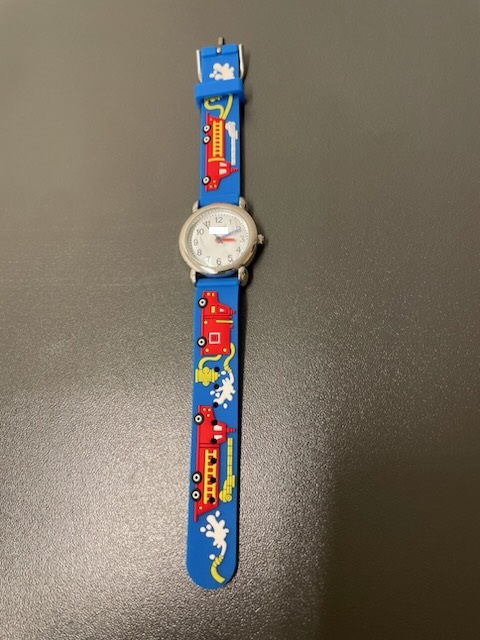Batteridrivet armbandsur med rund boett och mekanisk (analog) tidvisning. Armbandsuret är avsett för barn.
Armbandsurets boett har en diameter av ca 28 mm, är enligt uppgift tillverkad av metallegering och bakboetten är tillverkad av rostfritt stål. Härdat mineralglas skyddar den vita urtavlan. Armbandet har en bredd av 14 mm, ett spänne av rostfritt stål, består av gummi och dess utsida är bl.a. utsmyckad med röda brandbilar.
Uret levereras tillsammans med blyertspenna SE BTI TV-2022-16097-2, tuschpenna SE BTI TV-2022-16097-3, pennvässare SE BTI TV-2022-16097-4, linjal SE BTI TV-2022-16097-5 och radergummi SE BTI TV-2022-16097-6. Artiklarna är förpackade gemensamt i en ask i form av ett pennskrin SE BTI TV-2022-16097-7. Artiklarna tillsammans uppfyller inte villkoren för att klassificeras som en sats för försäljning i detaljhandeln, då artiklarna inte har tillräckligt samband sett till användningen. Detta beslut omfattar endast armbandsuret.