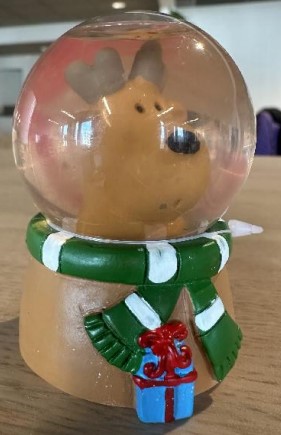 Prydnadsföremål av plast i form av en vätskefylld glob.
Artikeln har en rund bas av polyresin föreställande en ren försedd med halsduk och paket. Globen är placerad över renens huvud och fylld med vätska med synliga partiklar som ska efterlikna snöflingor. Genom att skaka globen virvlar partiklarna upp och bildar ett snöfall.
Artikeln är enligt uppgift 6,5 cm hög.