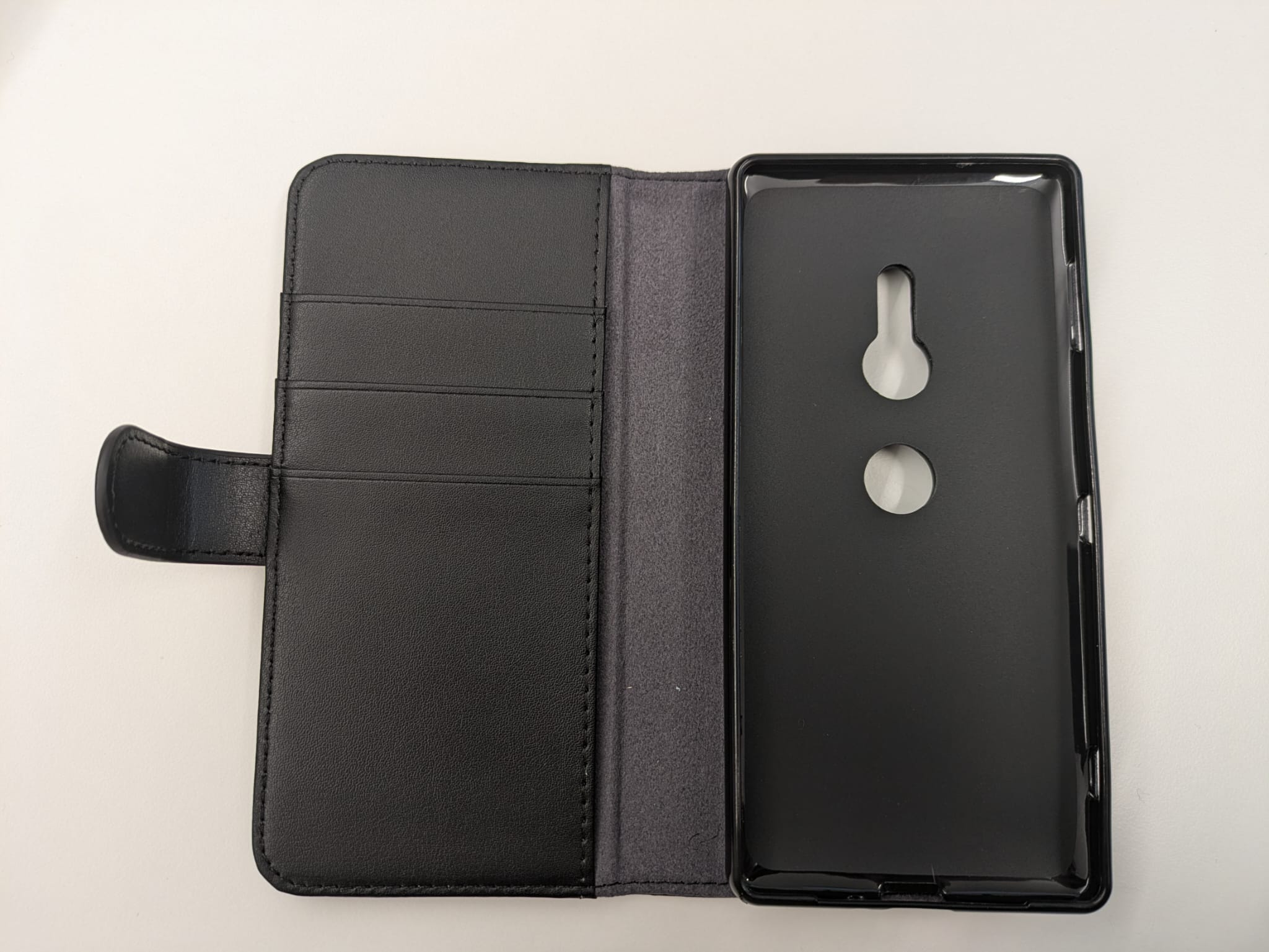 Fodral till en mobiltelefon (s.k. smartphone) enligt uppgift av äkta läder. Fodralet har rektangulär form med rundade hörn och magnetisk tillslutning. Baksidan av fodralet och innerskalet har utskärningar för telefonens kameralins, knappar, laddkontakt och dylikt. Insidan av fodralet är försett med tre slitsar för kort (s.k. kortfack), ett större fack bakom kortfacken där kontanter/kvitton kan förvaras och en hållare (s.k. innerskal) av plast (TPU) som håller fast telefonen.
Fodralet omsluter och skyddar telefonen genom att täcka dess baksida, sidor och framsida. Fodralet är avsett att bäras i ficka eller handväska.
Fodralet har måtten 15,8 x 8 x 1,5 cm (L x B x H).