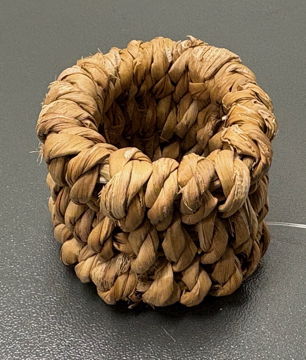 Cylinderformad servettring av flätningsmaterial med måtten ca 4,5 x 4 cm (B x H).
Varan är avsedd att användas vid dukning för att placera en servett i.
Servettringen är enligt uppgift tillverkad av sjögräs, vilket har tvinnats samt trätts över tre ringformade stommar.
Varan säljs i förpackning om sex stycken.