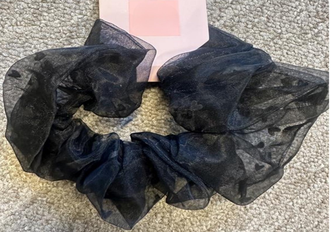 Konfektionerat beklädnadstillbehör i form av ett elastiskt hårband (en s.k. scrunchie).
Varan är avsedd att användas för att samla och hålla ihop håret.
Hårsnodden består enligt uppgift av ett elastiskt band (syntetiskt latex) som är helt täckt av ett vävt textilmaterial (tyll av polyester) försett med ett hjärtformat mönster. Hårsnodden är konfektionerad genom sömnad i form av en ögla.
Varan är fäst vid en pappryttare för försäljning i detaljhandeln.