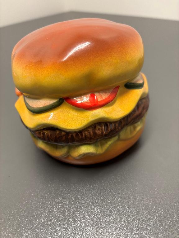 Prydnadsföremål av keramiskt material i form av en hamburgare med glaserad, blank yta.
Produkten är enligt uppgift endast avsedd som dekoration.
Varan är ungefärligt uppmätt till 11,5 cm i diameter och 10,5 cm hög. Den är ihålig och färgglatt dekorerad.
Enligt uppgift från sökanden är varan inte certifierad som handgjord. Ett varuprov har tillhandahållits och enligt analysrapport från Tullverkets laboratorium är produkten tillverkad av fajans.