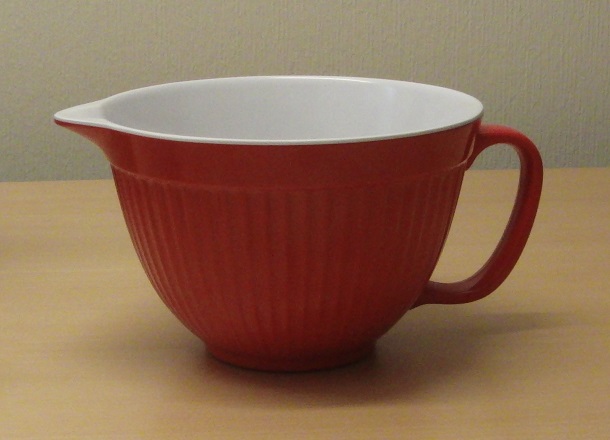 Skål
Köksartikel i form av en vispskål med pip och handtag. Utsidan är räfflad och på bottens undersida finns en gummilist. Skålen har en diameter av 20 cm.
Enligt uppgift är skålen tillverkad av plast (melamin) och avsänd från Kina. Skålens botten är märkt med made in China.