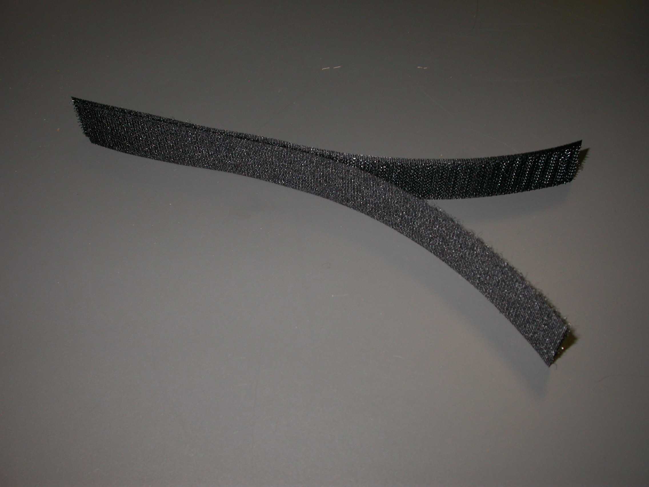 Ozka tkanina - sprimni trak (velcro), širine 20 mm, črne barve, sestavljen iz dveh med seboj mehansko spojenih delov:
-del, izdelan iz sintetičnih vlaken z vtkanimi sintetičnimi vlakni,
 ki tvorijo enostransko neprerezano, lasasto površino v obliki zank
-del, izdelan iz sintetičnih vlaken z vtkanimi monofilamenti, ki
 tvorijo enostransko prerezano, lasasto površino v obliki kljukic.

Pakirano v zvitke.