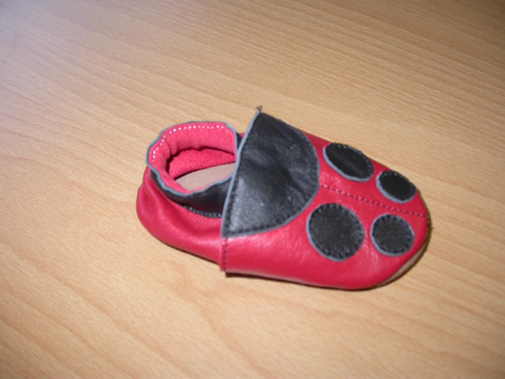 Otroški copati z zunanjim podplatom in zgornjim delom iz usnja. Copati so modre in rdeče barve, dolžina notranjika je 11 cm.