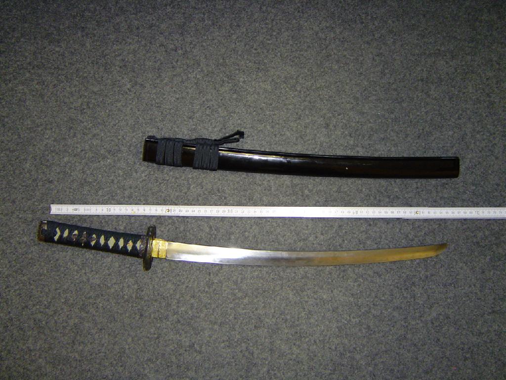 Izdelek je imitacija samurajske sablje, ki ima ostro konico. Pretežno je narejena iz navadnih kovin. Med rezilom in ročajem je nameščen kovinski ščitnik za roko premera 7 cm. Spravljena je v pripadajoči leseni nožnici črne barve. Ročaj je obdan s plastiko in prevezan s tekstilnim trakom. Skupna dolžina sablje je 66 cm in dolžina rezila 48 cm. Teža sablje in nožnice znaša 790 g.