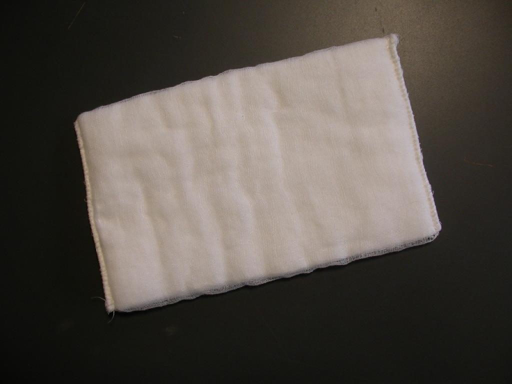 Nesterilna vpojna blazinica, velikosti 15 x 25 cm, izdelana iz vpojnega jedra iz bombažne vate, ki je prekrito s plastjo bombažne gaze. Blazinica je na dveh krajših robovih obšita.  
Služi kot obveza pri zdravljenju ran, za vpijanje krvi in drugih izločkov.
Uporablja se za medicinske namene.
Bistvo proizvoda predstavlja bombažna vata.
Pakirano po 100 kosov, za prodajo končnemu potrošniku, brez predhodnega prepakiranja (prodaja na drobno) in opremljeno z etiketo.